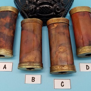 May include: Four antique brass-colored tubes with gold-colored trim and a decorative pattern. The tubes are labeled A, B, C, and D.