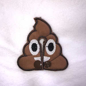 May include: Brown felt poop emoji patch with a white smile and eyes. The patch has two brown buttons on the bottom.