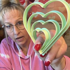 May include: A set of five green heart-shaped cookie cutters, nested inside each other. The cutters are made of plastic and are perfect for making cookies or other treats.