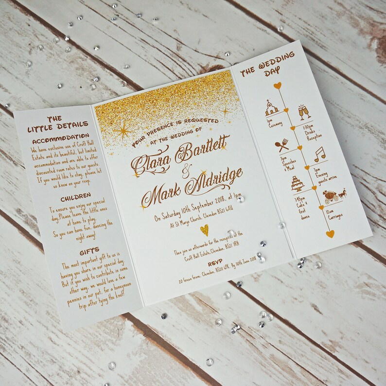 Puede incluir: Invitaci&oacute;n de boda con purpurina dorada sobre fondo blanco. La invitaci&oacute;n incluye los nombres de Clara Bartlett y Mark Aldridge, la fecha de la boda y la ubicaci&oacute;n de la ceremonia y la recepci&oacute;n. La invitaci&oacute;n tambi&eacute;n incluye una l&iacute;nea de tiempo de los eventos del d&iacute;a de la boda.