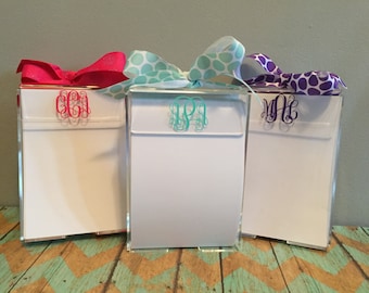Peut inclure: Trois blocs-notes en acrylique transparent avec des monogrammes personnalisés. Chaque bloc-notes est surmonté d'un ruban de couleur différente à pois. Les monogrammes sont "C.B.A", "T.P.I" et "M.H."