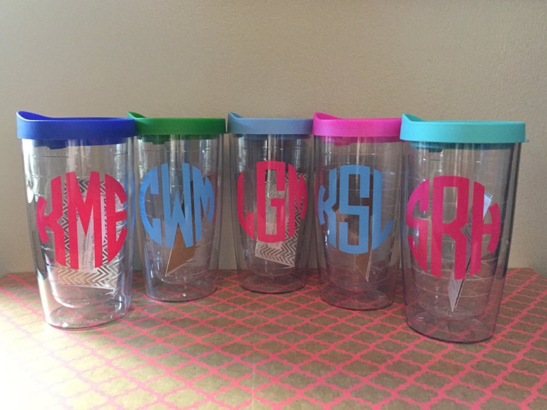 May include: Five clear plastic tumblers with lids in various colors, each with a different monogram in a contrasting color. The monograms are "YME", "CWM", "LGK", "KSL", and "SRH".