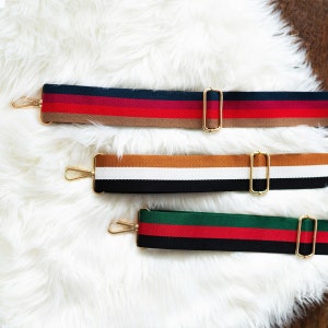 May include: Three striped fabric straps with gold clasps. The straps are red, white, and black; brown, white, and black; and green, red, and black.