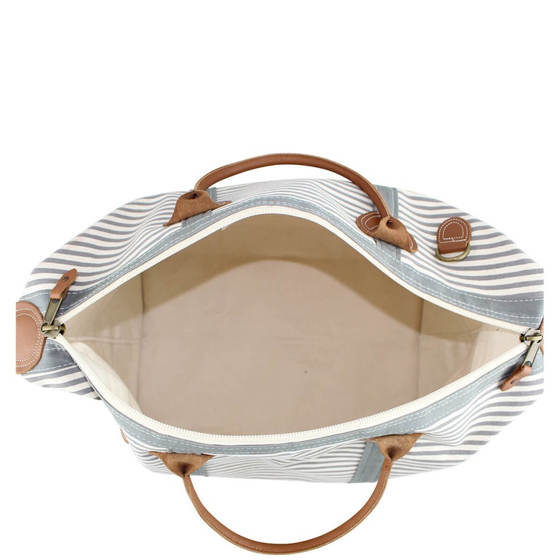 Pu&ograve; includere: Una borsa da viaggio a righe con manici in pelle marrone e chiusure a zip. La borsa &egrave; aperta e l'interno &egrave; bianco.