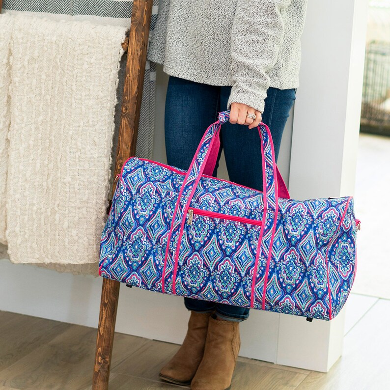 May include: A blue and pink patterned duffel bag with a pink zipper and handles. The bag is large enough to hold a weekend's worth of clothes.
