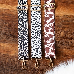 May include: Three different patterned fabric straps with gold metal clasps. The straps are leopard print, black and white polka dot, and brown and white cow print.
