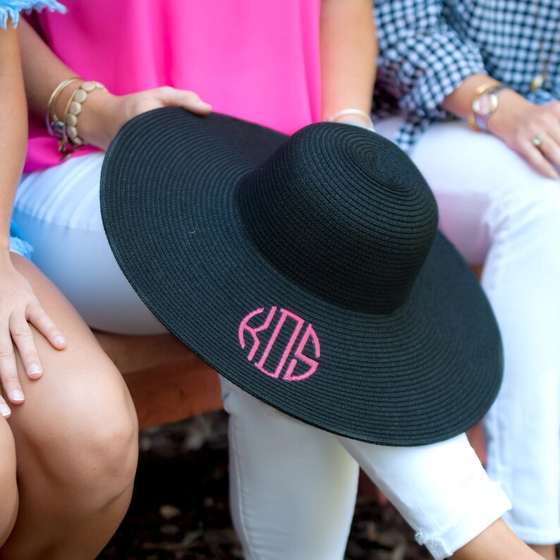 May include: A black wide-brimmed sun hat with a pink monogram "KGS" on the front.