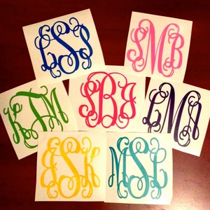 May include: Seven white vinyl stickers with different colored monograms. The monograms are in a script font and include the letters "SB", "LM", "ESK", "MSL", "KJM", "SSB", and "SM".