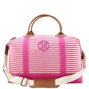 Pu&ograve; includere: Borsa da viaggio da fine settimana in tela a righe rosa e bianche con manici in pelle marrone e un cerchio monogrammato rosa sul davanti.