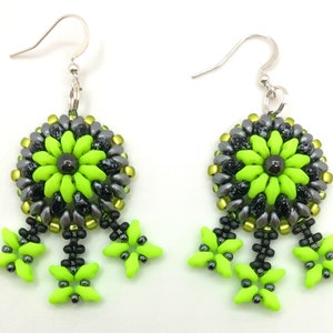 Peut inclure: Une paire de boucles d'oreilles pendantes avec un motif de fleur en perles vertes et argentées. Les boucles d'oreilles ont trois étoiles en perles vertes qui pendent du bas.
