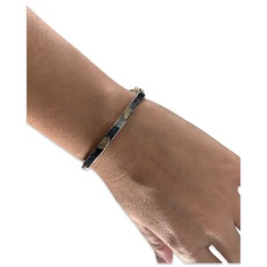 May include: A silver bangle bracelet with a black and gold snakeskin pattern.