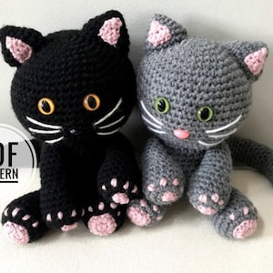 May include: Two crocheted cat toys, one black with yellow eyes and one grey with green eyes. Both cats have pink ears and paws. The text "PDF PATTERN" is visible in the image.