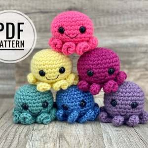 May include: Six crocheted octopus plushies arranged in a pyramid shape. The octopus are pink, yellow, purple, teal, blue, and lavender.