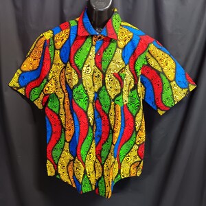 May include: A short-sleeved button-down shirt with a colorful abstract pattern in shades of red, yellow, green, and blue. The pattern is reminiscent of flames or waves.