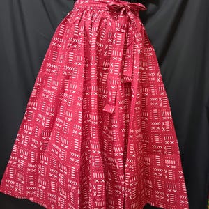 May include: A red maxi skirt with a white geometric pattern. The skirt has a tie at the waist.