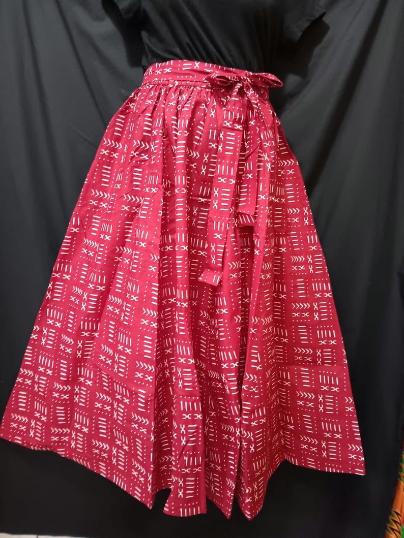 May include: A red maxi skirt with a white geometric pattern. The skirt has a tie at the waist.