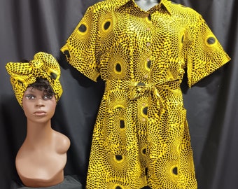 May include: A yellow and black patterned dress with a button-up front and a tie belt. The dress has short sleeves and a knee-length skirt. A matching head wrap is also included.