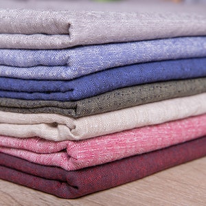 May include: A stack of fabric swatches in various colours and textures, including beige, blue, green, white, pink, and red.