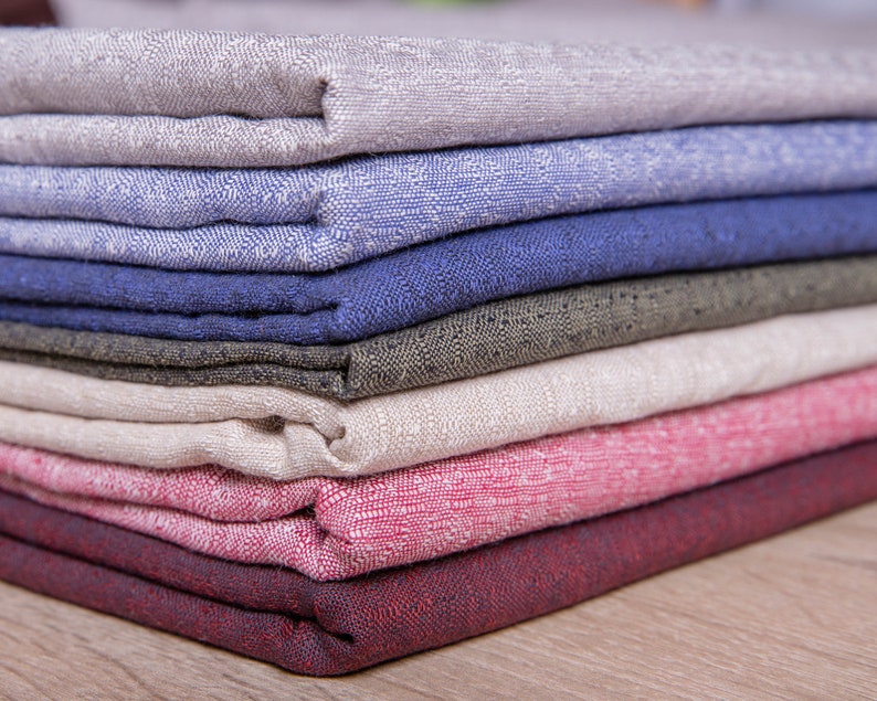 May include: A stack of fabric swatches in various colours and textures, including beige, blue, green, white, pink, and red.
