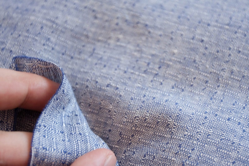 May include: Close-up of a blue and white patterned fabric with a textured weave. The fabric is soft and has a subtle sheen.