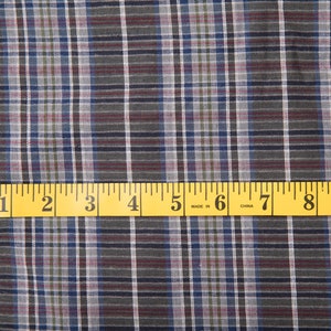 以下が含まれることがあります： 青、緑、赤の格子柄の生地のクローズアップ。下部に黄色のメジャーが置かれ、メジャーには「1、2、3、4、5、6、7、8、9」と「Made in China」と表示されています。