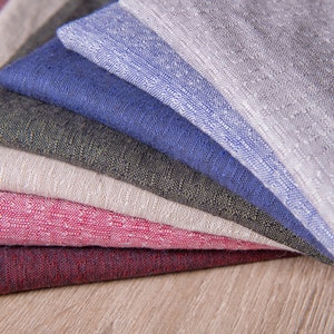 May include: A stack of six fabric swatches in various colours and textures, including grey, blue, green, beige, pink, and burgundy.