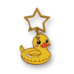 May include: A yellow rubber ducky keychain with a gold star-shaped clasp. The duck has an orange beak, pink cheeks, and a white inner tube design. The keychain is a fun accessory.