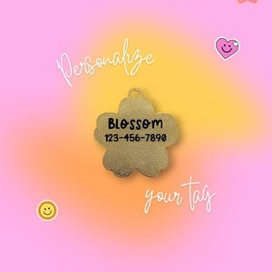 May include: A gold-colored, flower-shaped pet tag with the name "BLOSSOM" and a phone number. The tag is centered on a pink and yellow gradient background. The words "Personalize your tag" are written in cursive.