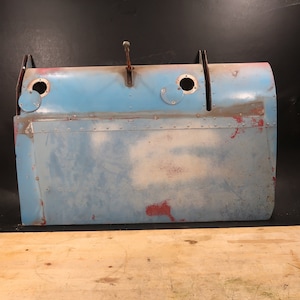 May include: A blue metal panel with rivets and two round holes. The panel has some rust and faded paint.