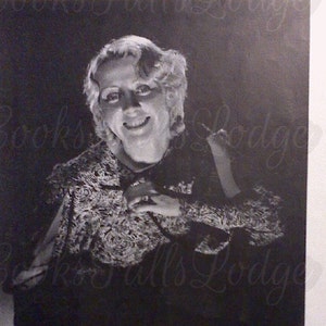 May include: Black and white photograph of actress Joan Blondell, smiling and seated. She wears a patterned top and has her hair styled in waves. The text "Blondie" is below the image.