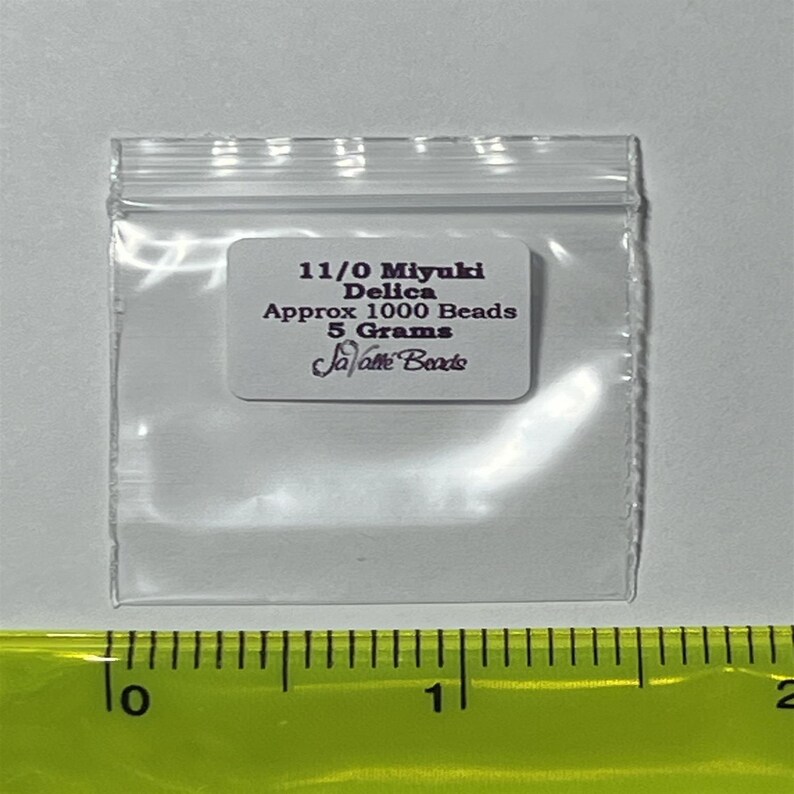 Pu&ograve; includere: Un piccolo sacchetto di plastica trasparente contenente perline Miyuki Delica 11/0. Il sacchetto ha un'etichetta bianca con il testo "11/0 Miyuki Delica Approx 1000 Beads 5 Grams Ja-lotte Beads".