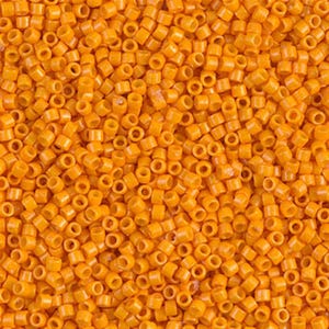 May include: A close-up image of a large quantity of small, round, orange beads. The beads are all the same size and shape, and they are arranged in a random pattern.