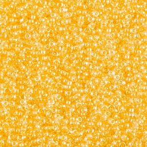 May include: A close-up image of a large quantity of small, round, translucent yellow beads.