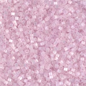 May include: A close-up view of a large quantity of small, opaque, light pink, round seed beads. The beads have a slight iridescent sheen.