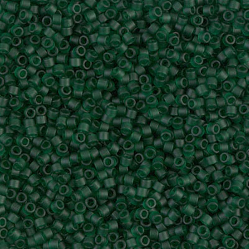 May include: A close-up image of a large quantity of small, round, opaque green beads. The beads are arranged in a random pattern, creating a textured surface.