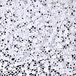 May include: A close-up image of a large quantity of small, white, opaque, round seed beads. The beads are arranged in a random pattern and are all the same size.