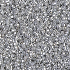 May include: A close-up image of a large quantity of small, silver-colored seed beads. The beads are round and have a slightly iridescent finish.