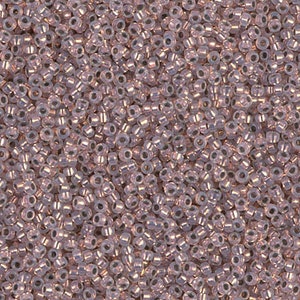May include: A close-up image of a large quantity of small, round, iridescent glass beads. The beads are a light pink color with a subtle shimmer.