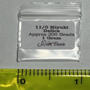 Pu&ograve; includere: Un piccolo sacchetto di plastica trasparente contenente perline Miyuki Delica 11/0. Il sacchetto ha un'etichetta bianca con testo nero che recita "11/0 Miyuki Delica Approx 200 Beads 1 Gram Savatte Beads".