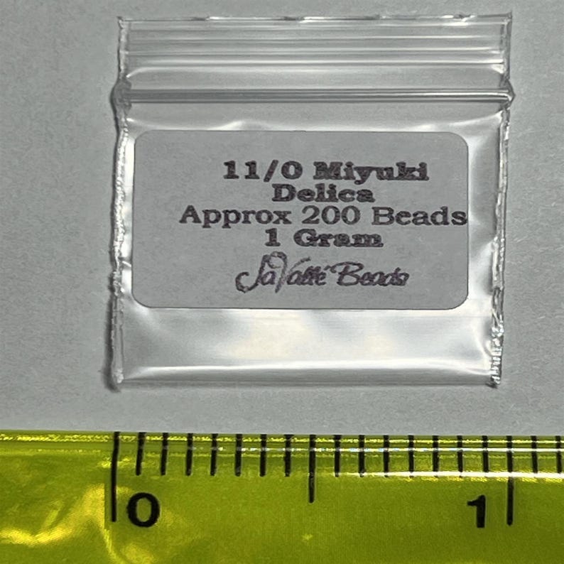 Pu&ograve; includere: Un piccolo sacchetto di plastica trasparente contenente perline Miyuki Delica 11/0. Il sacchetto ha un'etichetta bianca con testo nero che recita "11/0 Miyuki Delica Approx 200 Beads 1 Gram Savatte Beads".