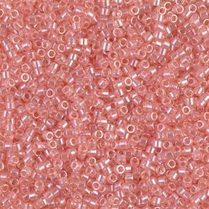 May include: A close-up shot of a pile of small, translucent, light pink seed beads. The beads are cylindrical with a hole running through the center, and they are scattered randomly, creating a textured surface. The beads are uniform in size and shape.