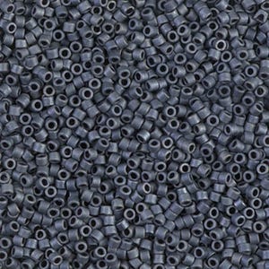May include: A close-up view of a large quantity of small, dark gray seed beads. The beads are round and have a hole in the center.