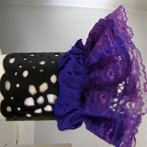 K&ouml;nnte beinhalten: Eine schwarze Spitzenmanschette mit einer violetten Spitzen&uuml;berlagerung. Die Manschette hat einen gewellten Rand und ein gepunktetes Muster.