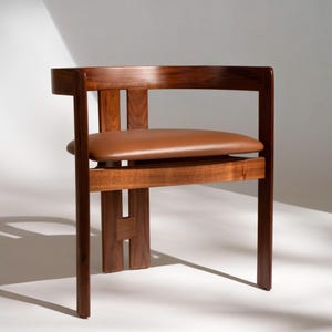 May include: A wooden chair with a brown leather seat. The chair has a minimalist design with a rectangular back and a seat that appears to float. The wood has a rich, dark finish. The chair's dimensions are approximately 30 inches high, 20 inches wide, and 20 inches deep.