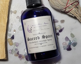 May include: A blue glass bottle with a black spray nozzle and a white label that reads "Lavender Moon Apothecary by eSCENTials Aroma Sacred Space Smokeless Smudge Spray Aromatherapy + Crystals + Intention".