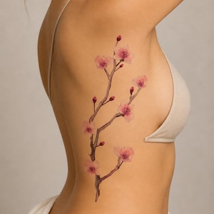 May include: XL temporary tattoo featuring a delicate cherry blossom branch with pink flowers and buds. The tattoo measures 5 x 10 inches (12.7 x 25.4 cm).