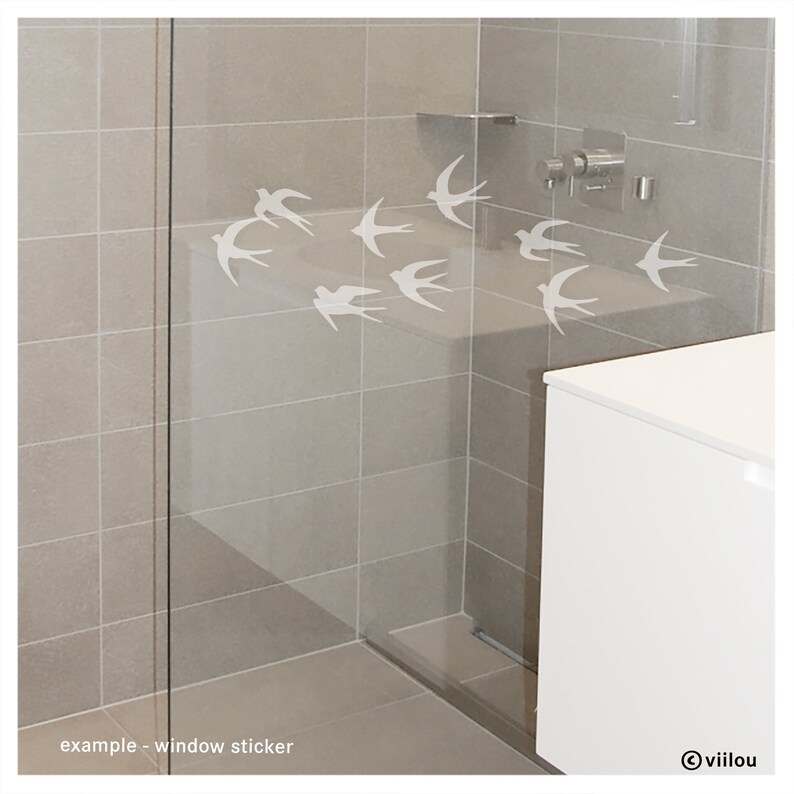 Pu&ograve; includere: Un set di adesivi bianchi a forma di rondine applicati su una parete doccia in vetro. Il design presenta otto sagome di uccelli in diverse posizioni di volo, creando un effetto stormo. Il testo "example - window sticker" e "viilou" sono visibili.