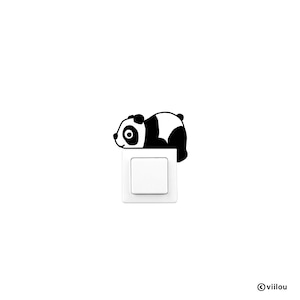 Puede incluir: Una pegatina de oso panda en blanco y negro está colocada sobre un interruptor de luz blanco. El panda está tumbado, añadiendo un toque lúdico a un objeto funcional. La imagen tiene un fondo blanco.