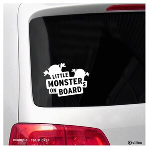 以下が含まれることがあります： 2 つの漫画のモンスターと「Little Monsters On Board」というテキストが書かれた白い車のステッカー。