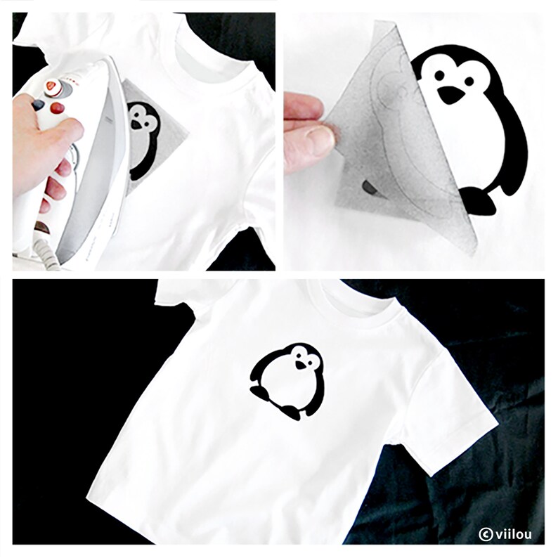 Puede incluir: Una camiseta blanca con un dise&ntilde;o de ping&uuml;ino negro planchado. El ping&uuml;ino est&aacute; mirando hacia adelante con las alas extendidas y tiene un peque&ntilde;o pico y ojos.